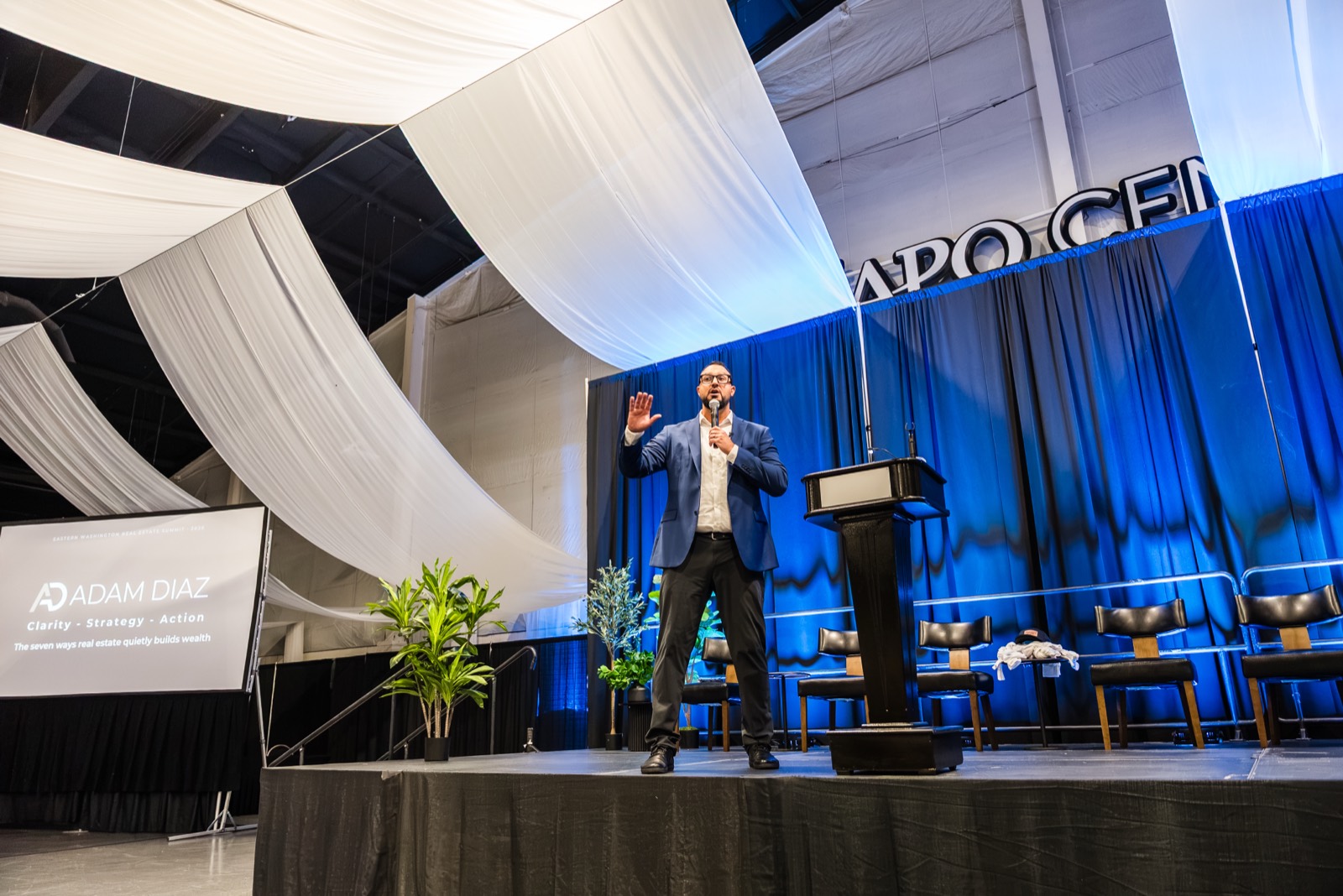 Adam Diaz keynoting on stage with his name and Clarity - Strategy - Action on the screen